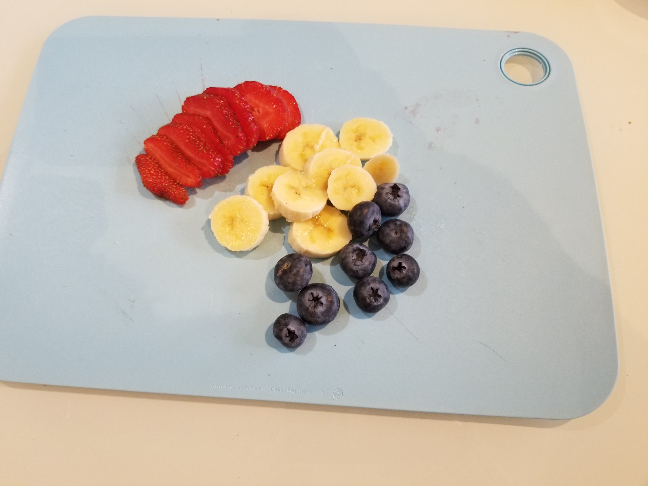 Easy Easter recipe step three - pieces of cut berries and banana on cutting board