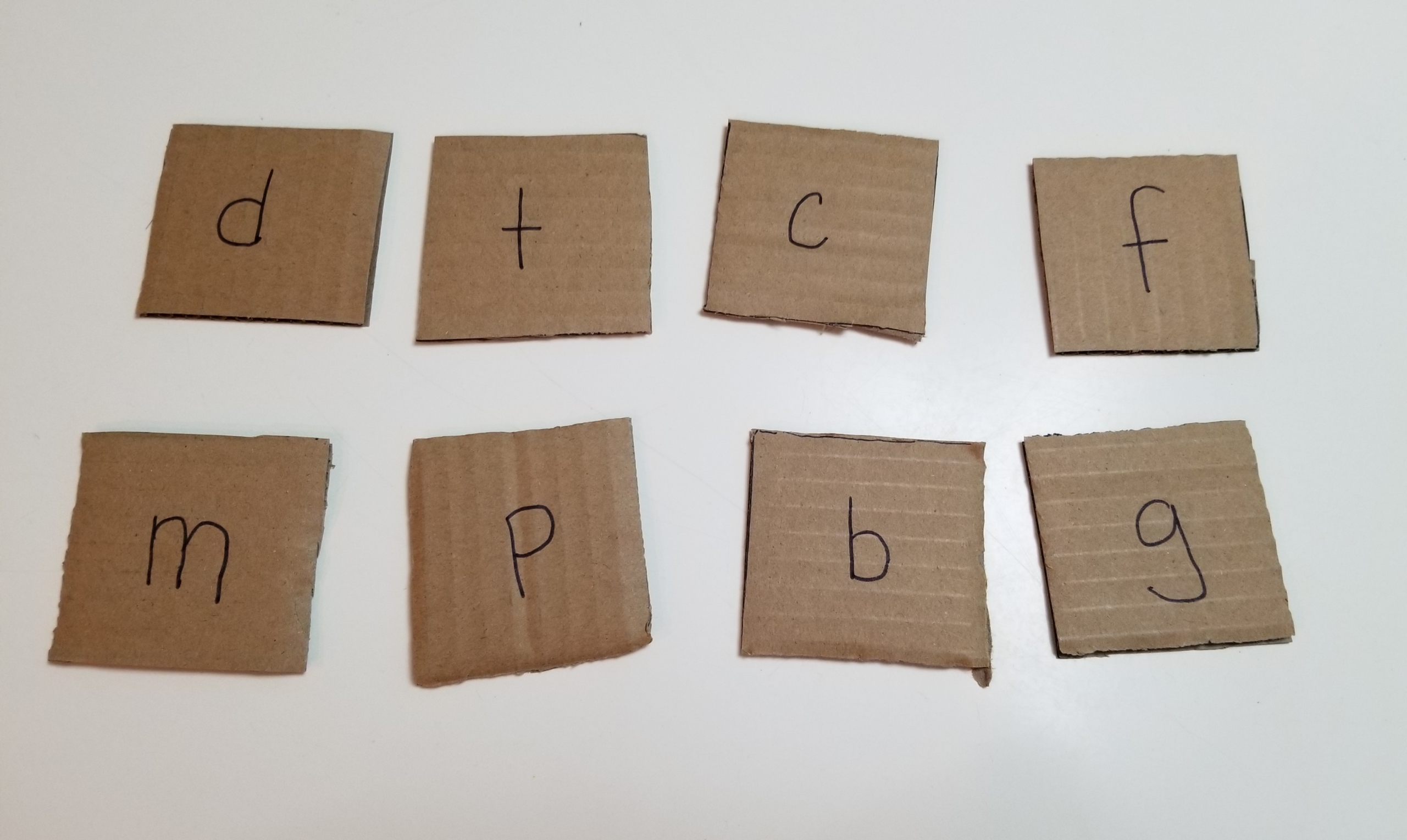 cardboard cut into squares with letters written on each one