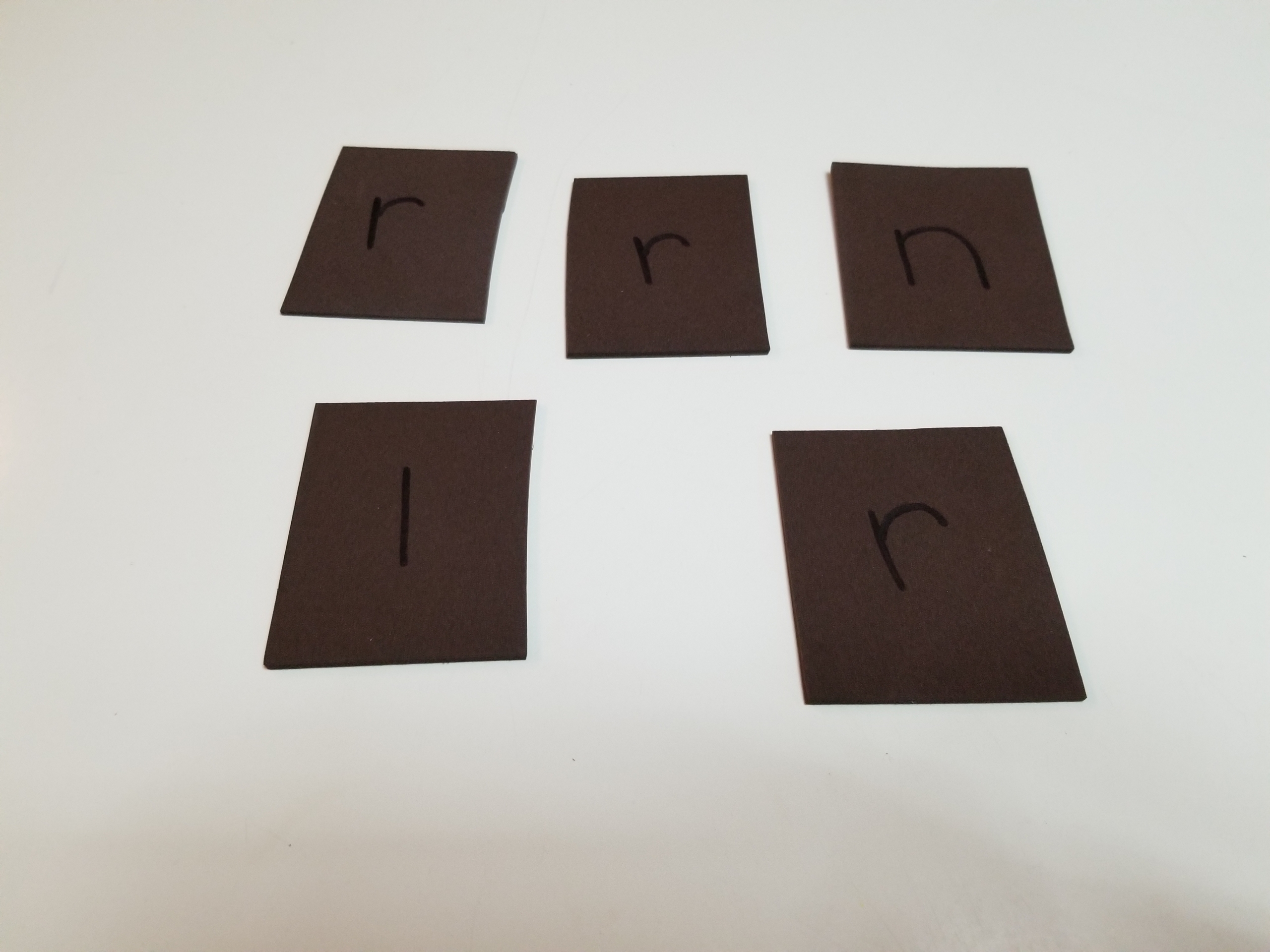 dark brown construction paper cut into squares with letters drawn on each square