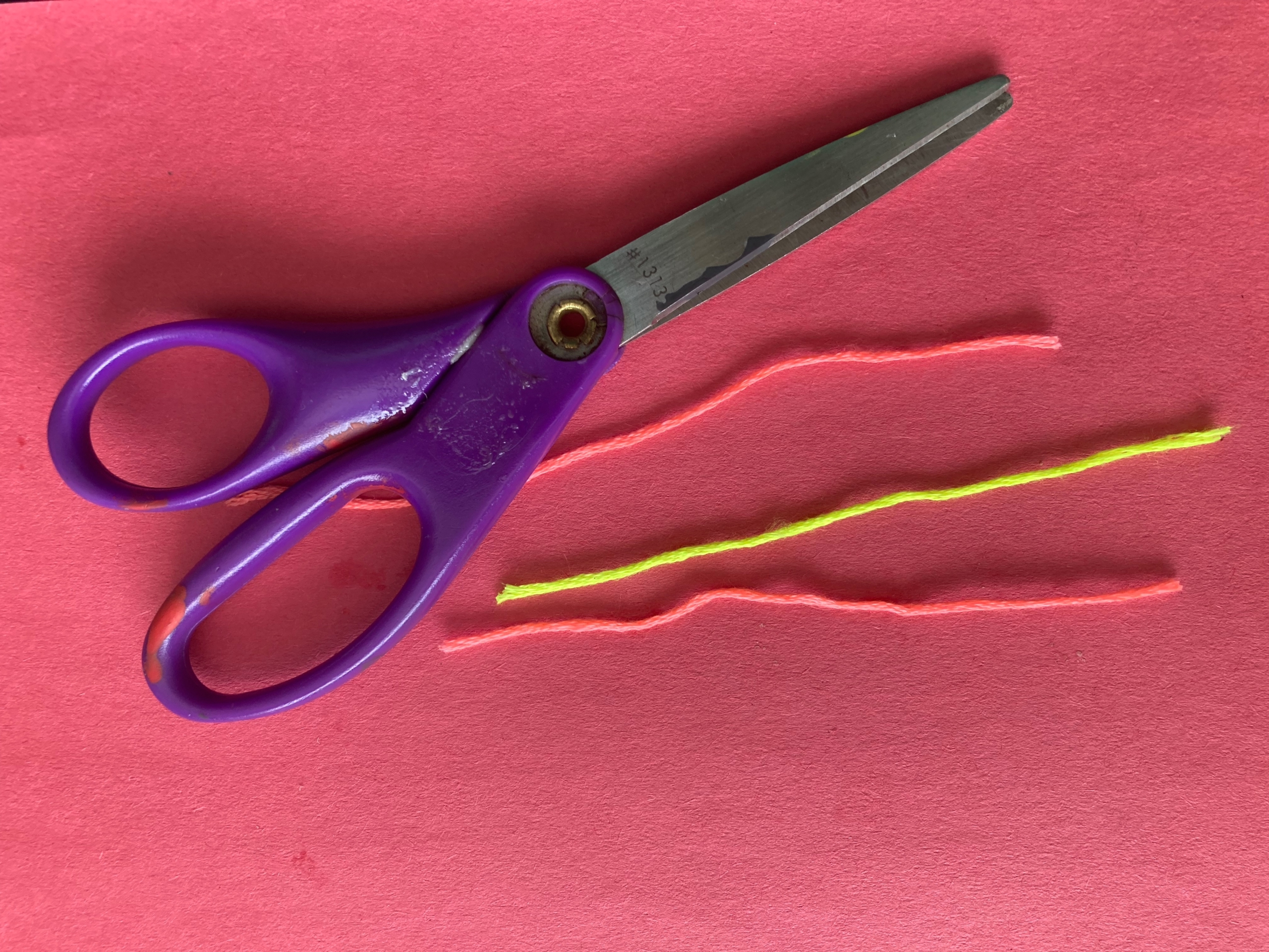 scissors next to three pieces of string