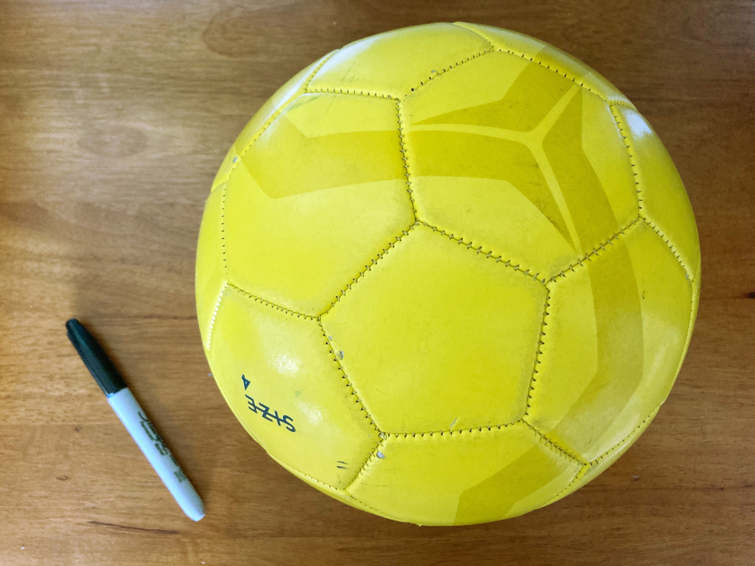 Yellow soccer ball with sharpie next to it