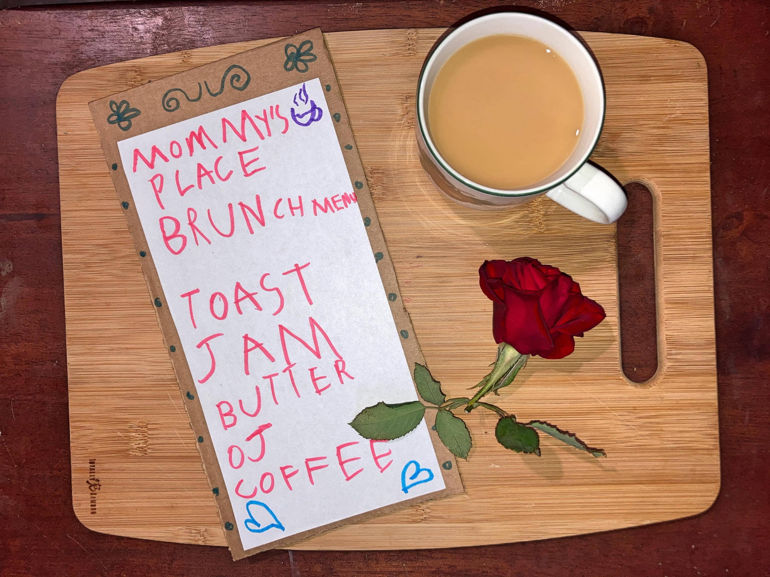 Cup of coffee, menu, and rose sitting on breakfast tray
